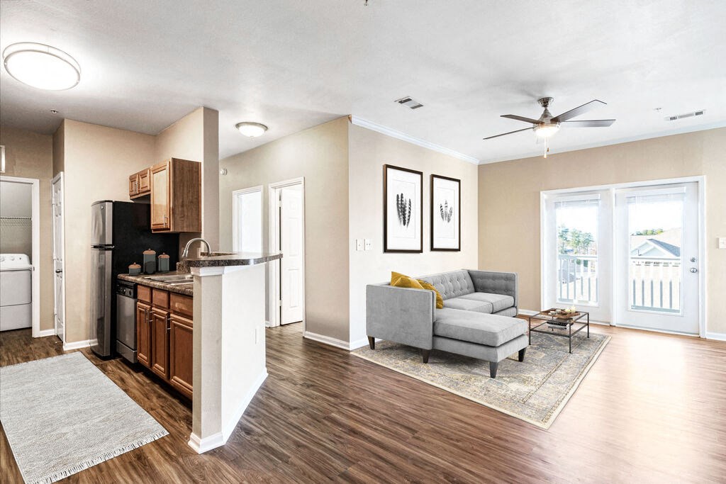 a living room with a couch and a coffee table next to a kitchen with a stove and at Tradition at Stonewater, Cary