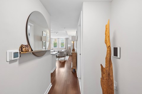 A long hallway with a mirror on the wall and a wooden sculpture on the other.