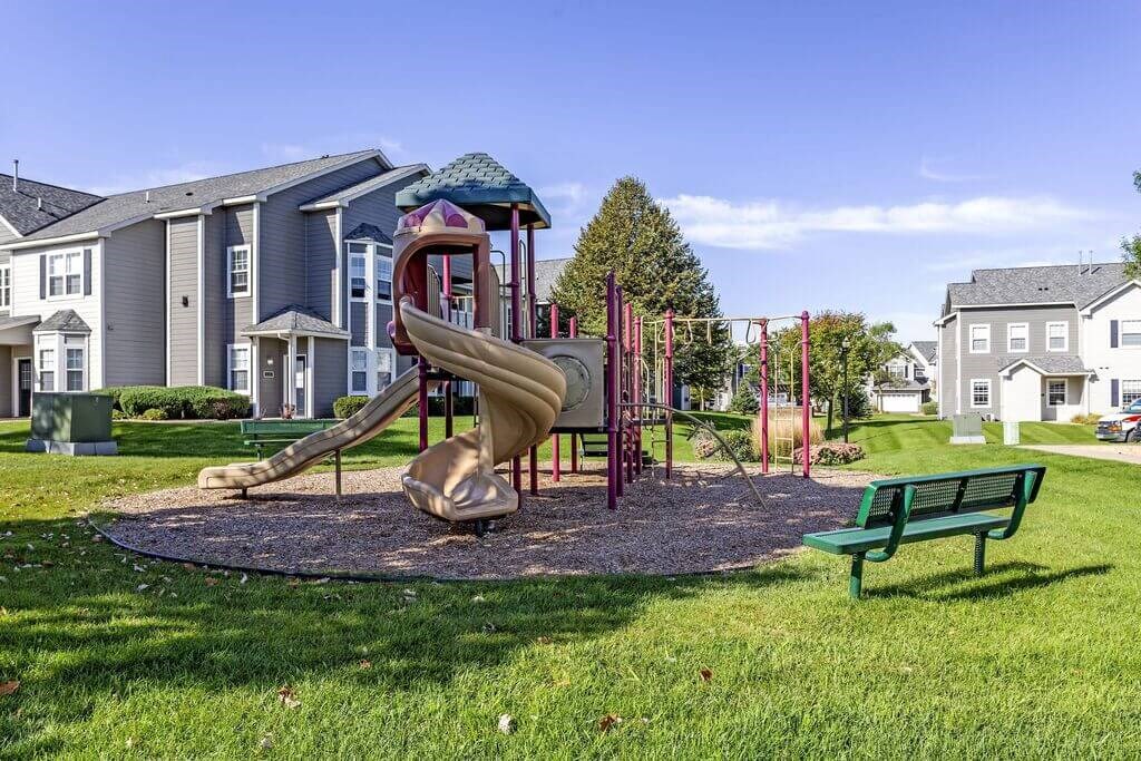 a playground with a slide and a bench in front of a building