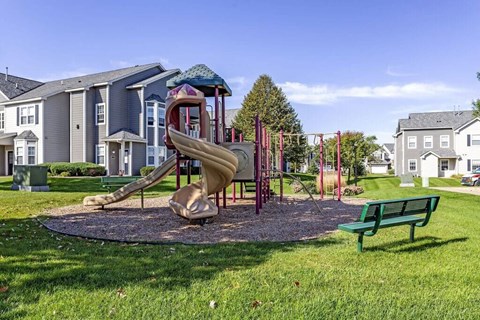 a playground with a slide and a bench in front of a building