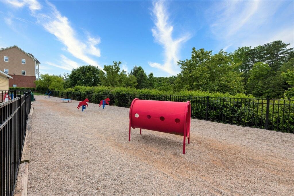 a large red barrel sits in the middle of a gravel path on a sunny day