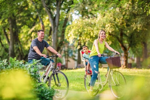 a man and woman riding bikes with a child on the back