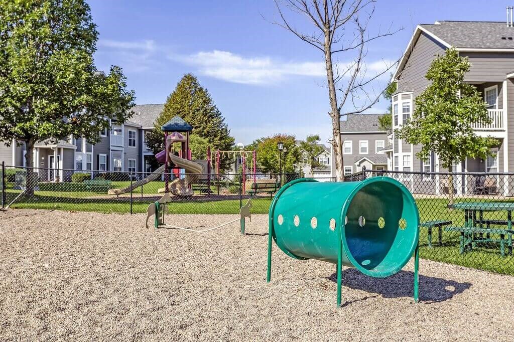 a playground with a slide and monkey bars in front of a house