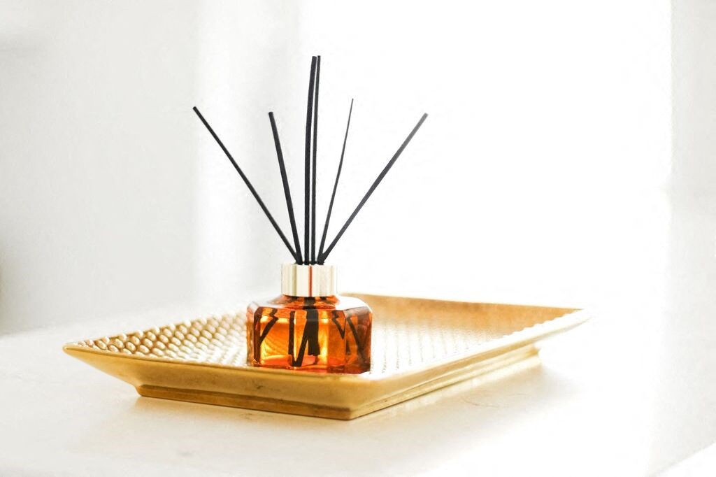 a diffuser sitting on a tray with a black reed diffuser on top of it