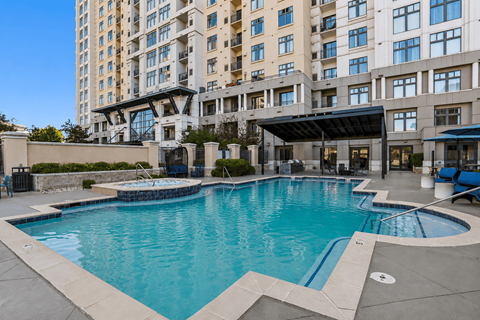 A large swimming pool in front of a multi-story apartment building.