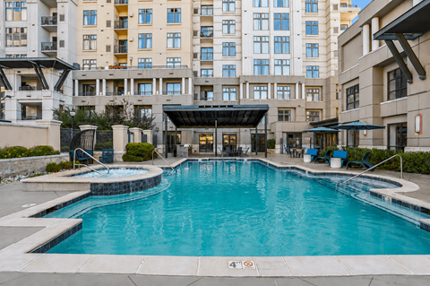 A large swimming pool in front of apartment buildings.