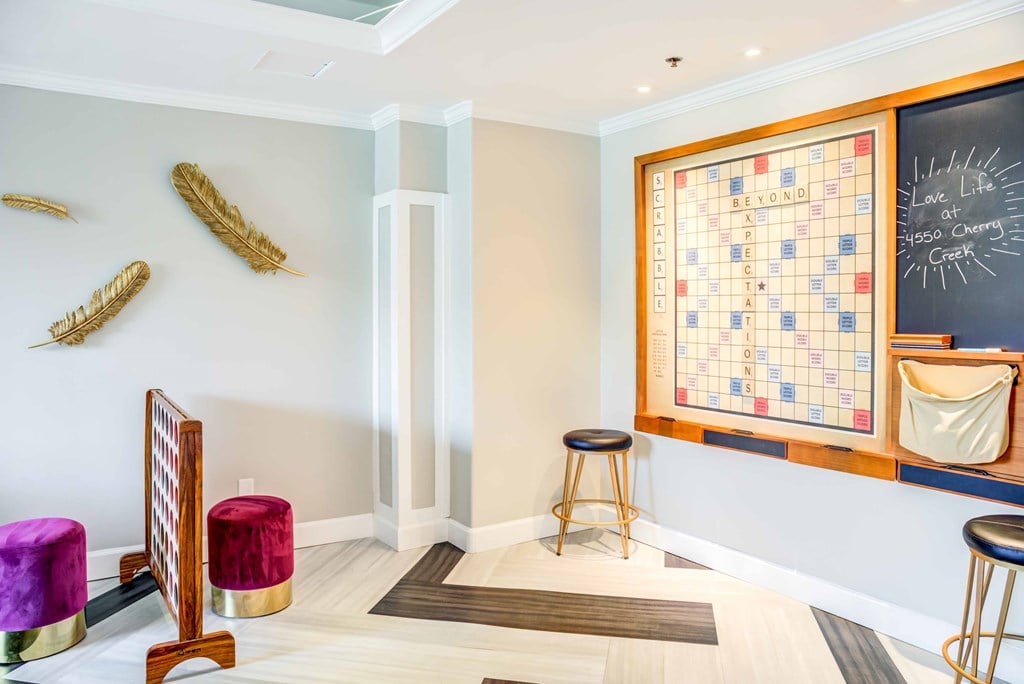 A room with a Scrabble board on the wall and a wooden chair.
