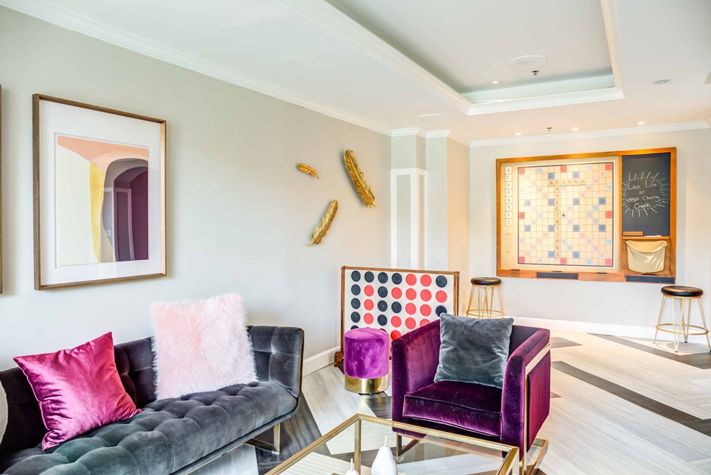 A living room with a purple couch and a chess board on the wall.