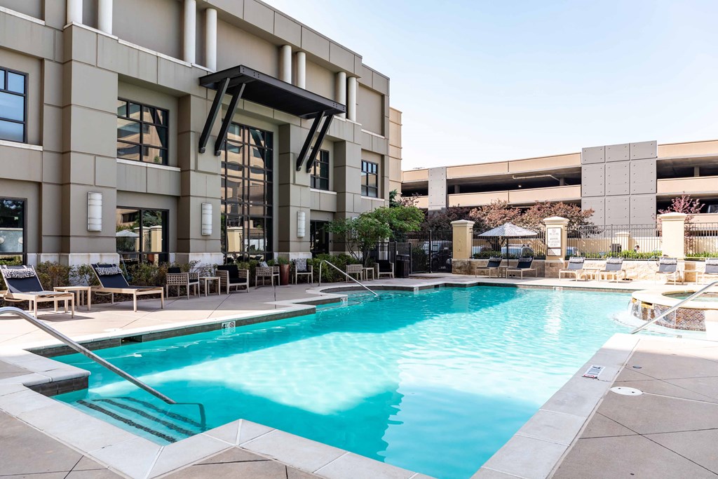 A swimming pool in front of a building with a sun lounger.