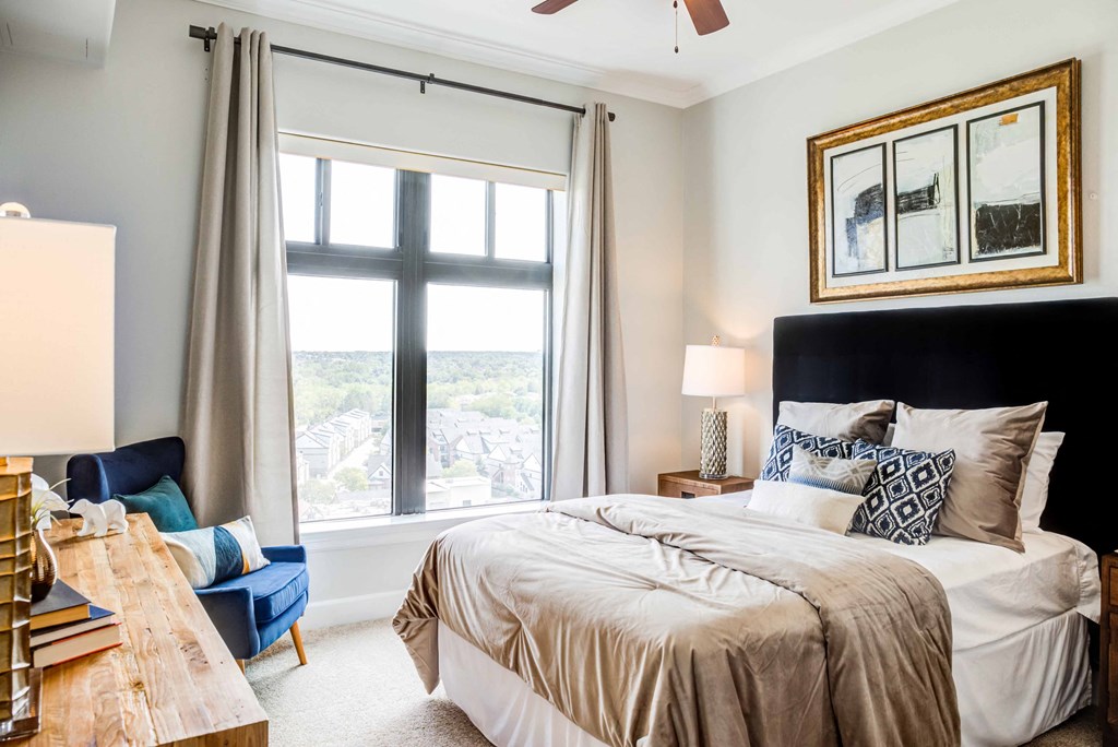A bedroom with a large bed and a view of the city through the window.