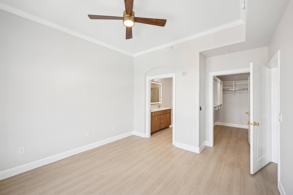 A room with a ceiling fan and light fixture, and a doorway leading to another room.