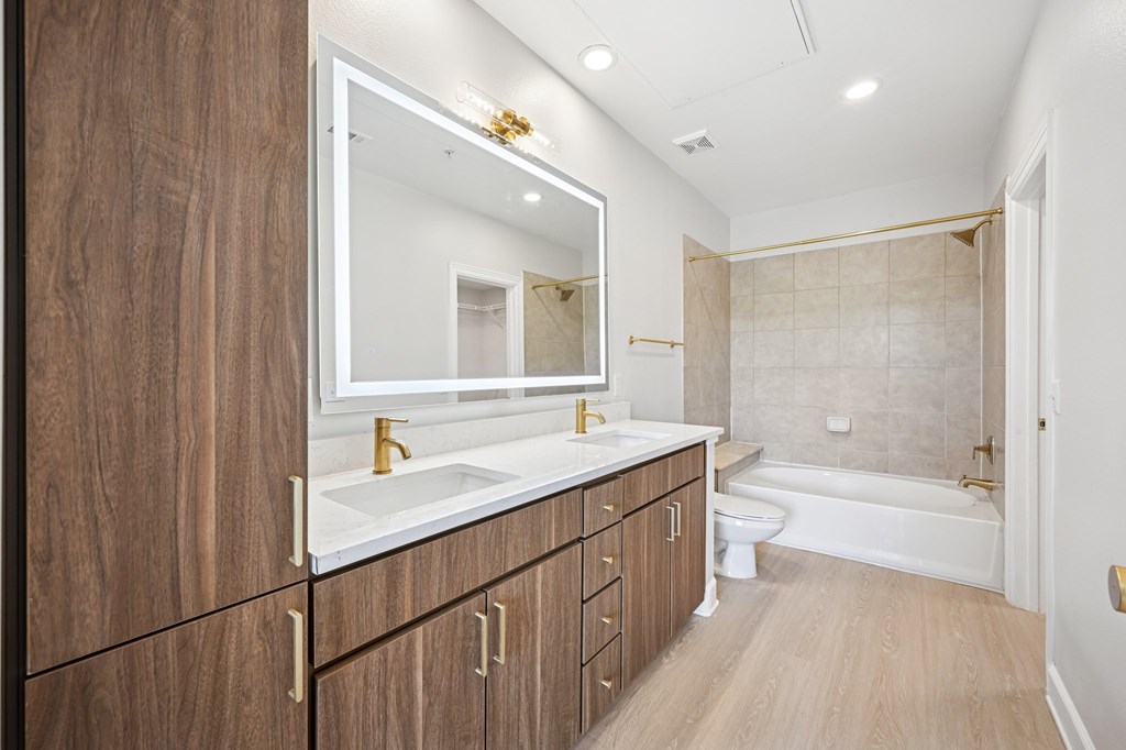 A bathroom with a sink, mirror, and bathtub.
