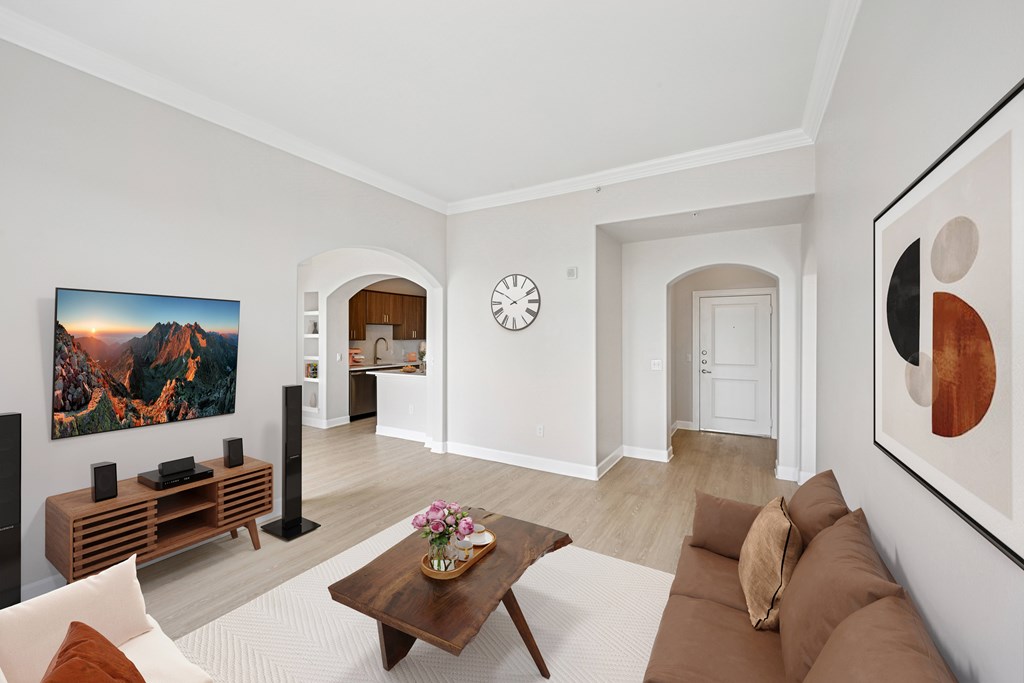 A living room with a brown couch, a painting on the wall, and a clock on the wall.