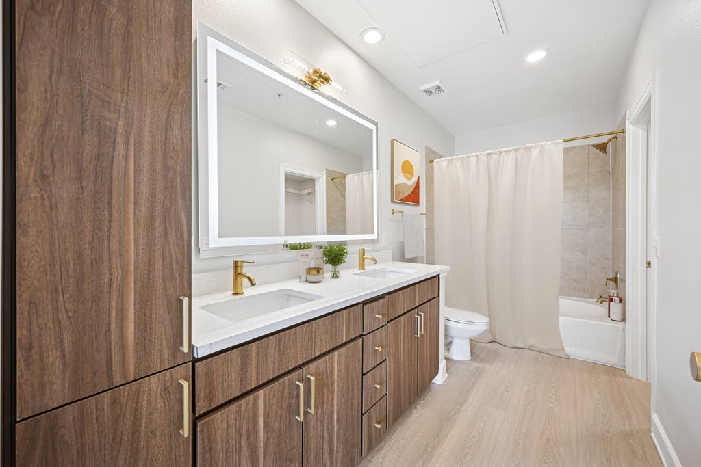 A bathroom with a sink, mirror, and wooden cabinets.