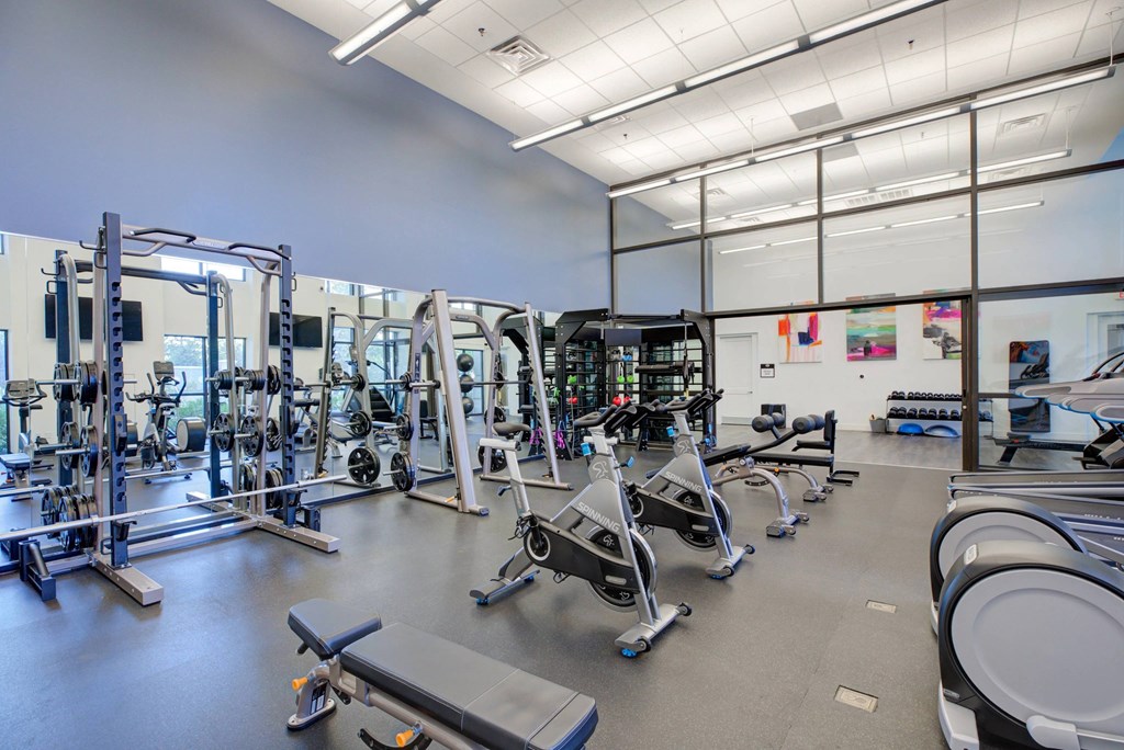 A gym with a variety of equipment including treadmills, weights, and exercise machines.