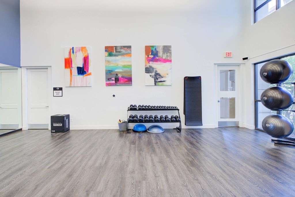 A room with a wooden floor and a few pieces of art on the wall.