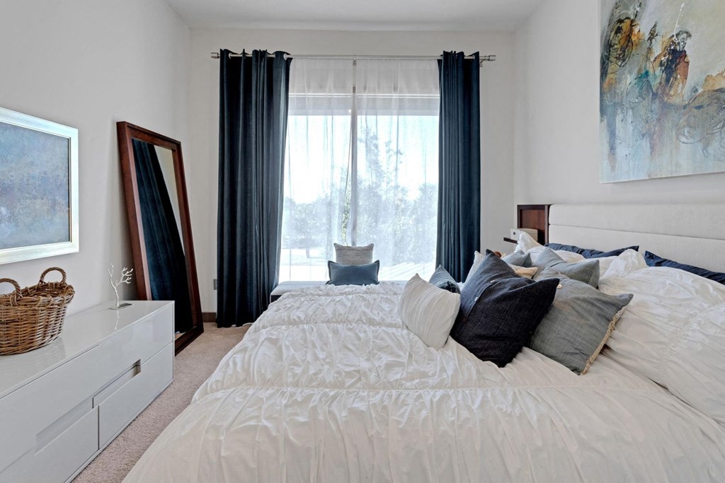 a bedroom with a large bed and a window with curtains