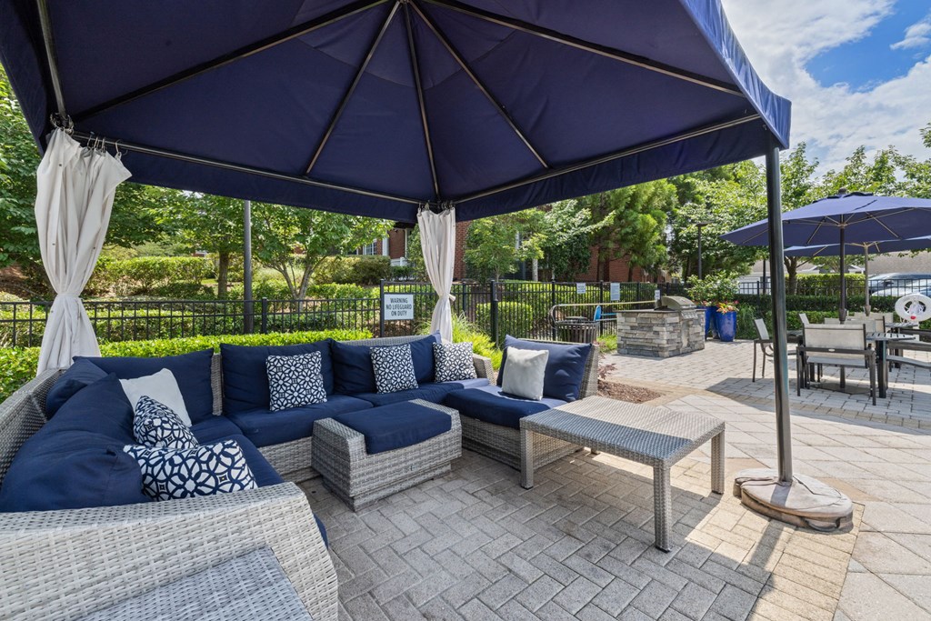 a patio with couches and umbrellas and tables at Tradition at Stonewater, North Carolina