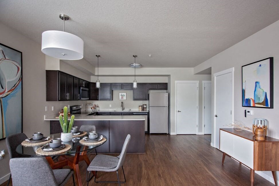 a dining area with a table and chairs and a kitchen in the background