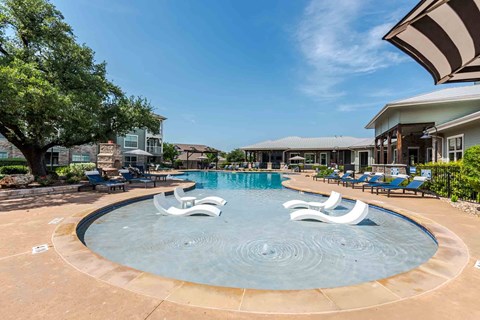 A round pool with a water feature in the middle at 95twenty Apartments, Austin