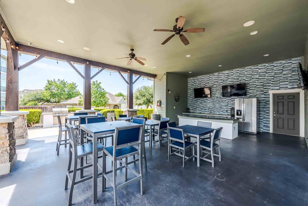 A patio with a table and chairs and a ceiling fan.