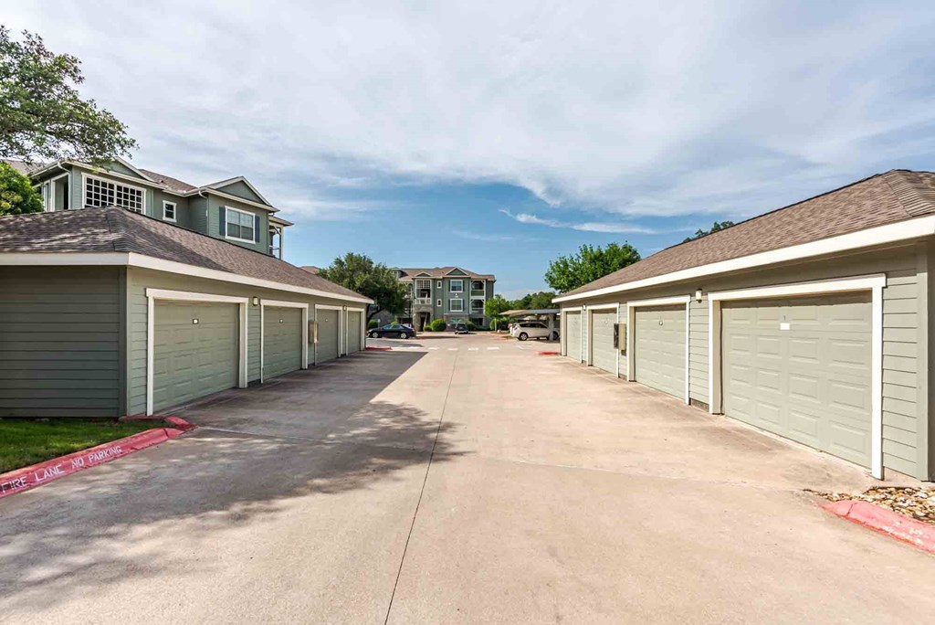 A row of garages with a driveway in between them.