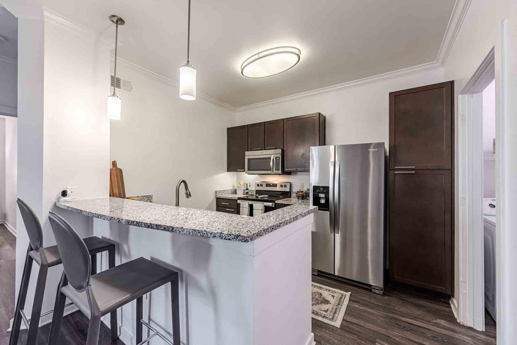A kitchen with a bar area and a refrigerator.