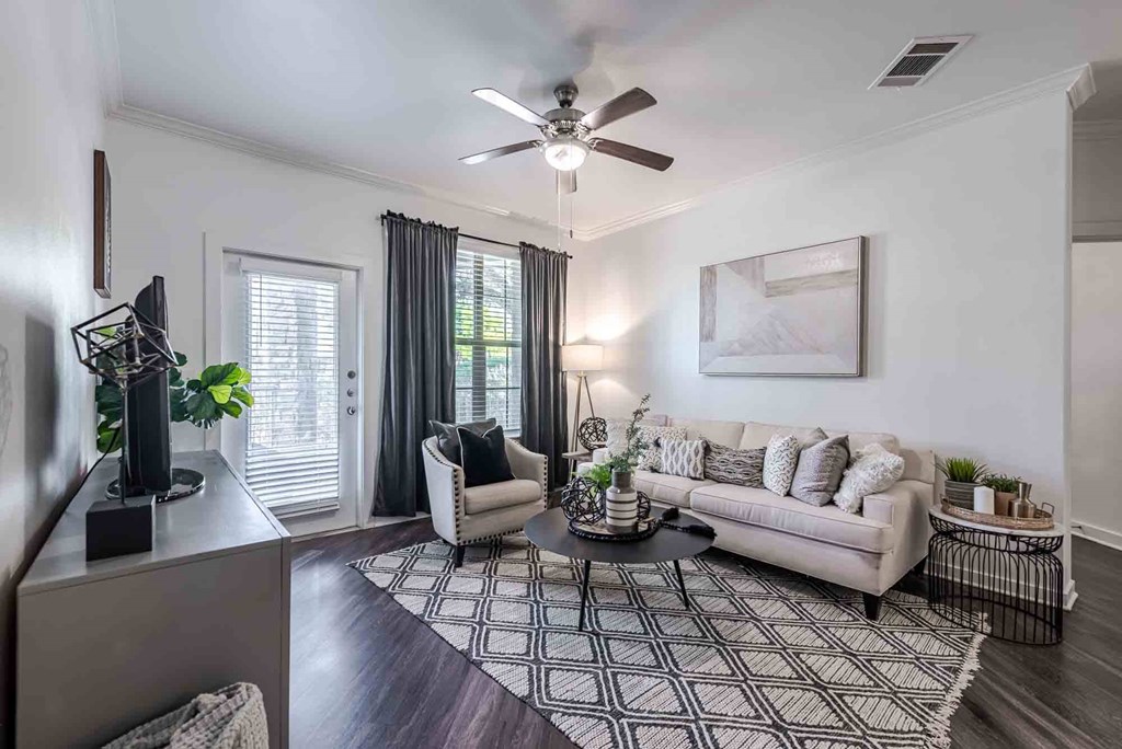 A living room with a white couch, a coffee table, and a ceiling fan.
