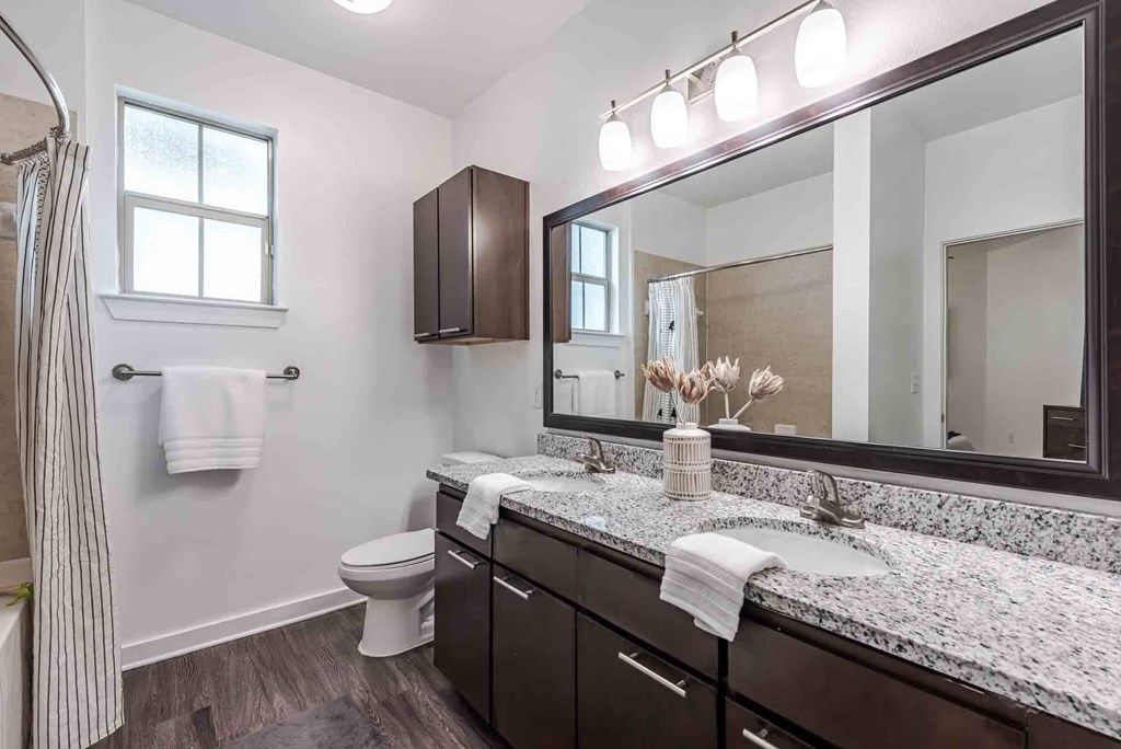 A bathroom with a toilet, sink, and mirror.