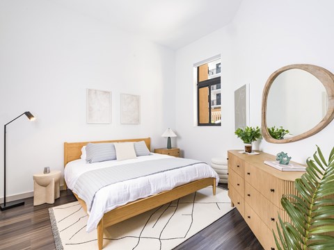 A bedroom with a large bed and a wooden dresser.