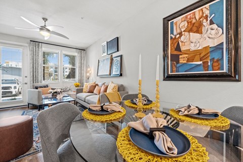 A dining room with a table set for two and a painting on the wall.