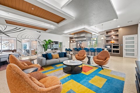 A living room with a blue rug and two orange chairs.