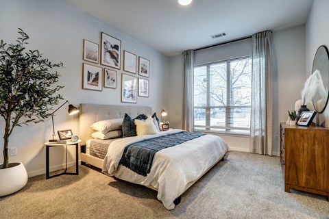 a bedroom with a large window and framed pictures on the wall at Arista Uptown Apartments, Broomfield