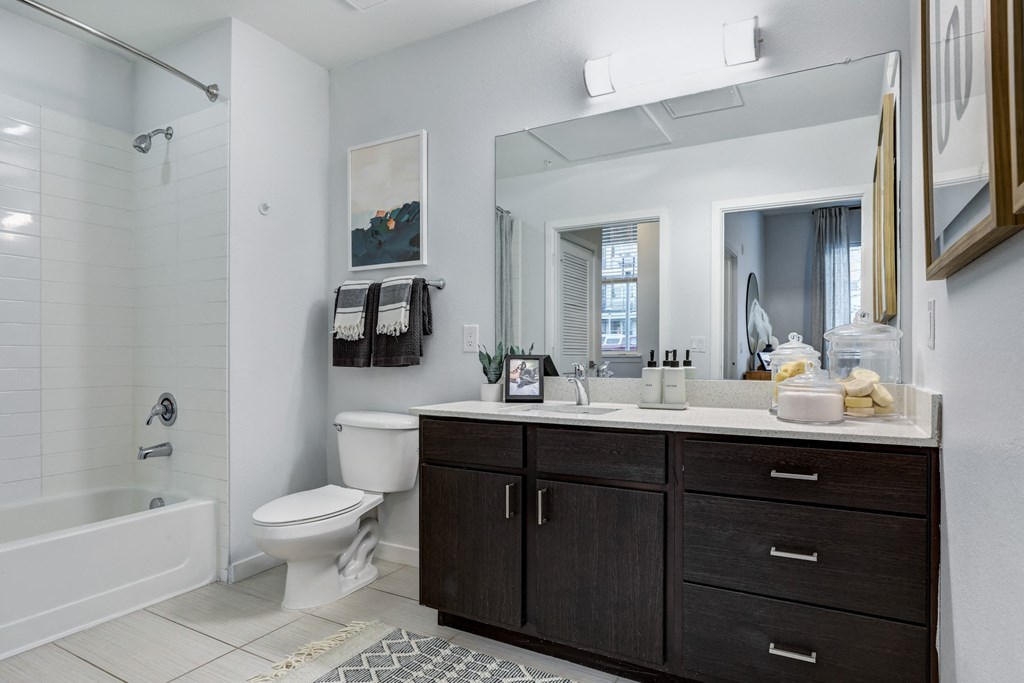 a bathroom with a toilet sink mirror and shower in a 555 waverly unit