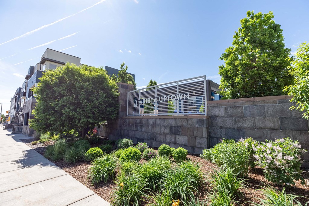 a stone retaining wall with a metal sign on it and trees in the background