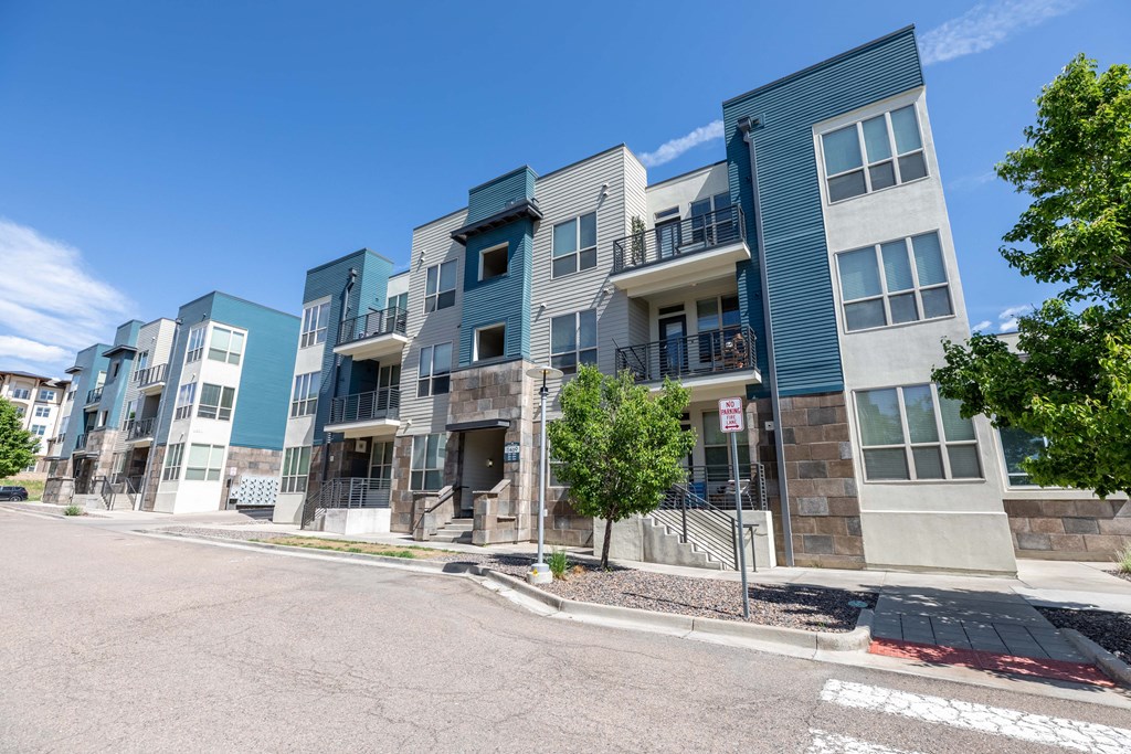 a row of apartment buildings on a street with a blue sky in the background