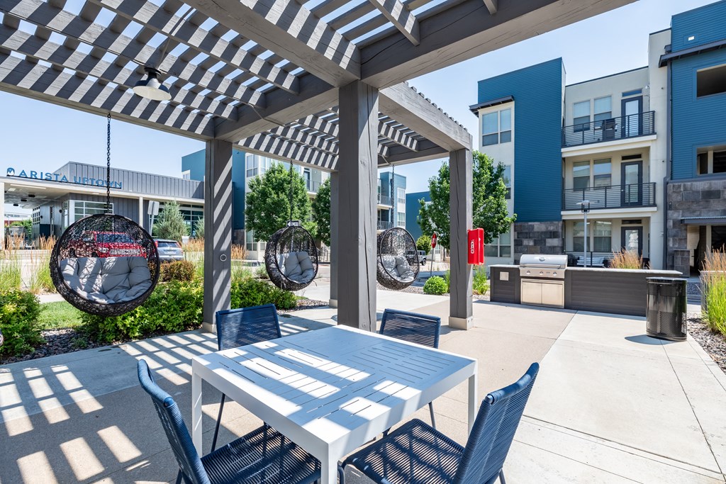 a patio with a white table and blue chairs