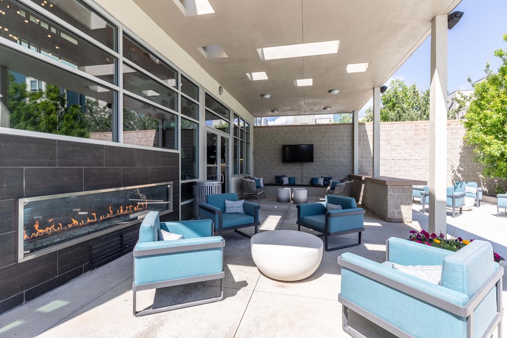 an outdoor lounge area with blue chairs and a fireplace