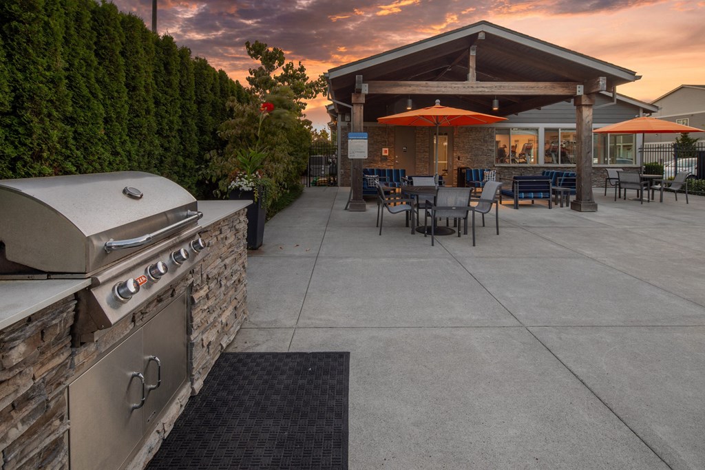 a patio with a grill and tables with umbrellas