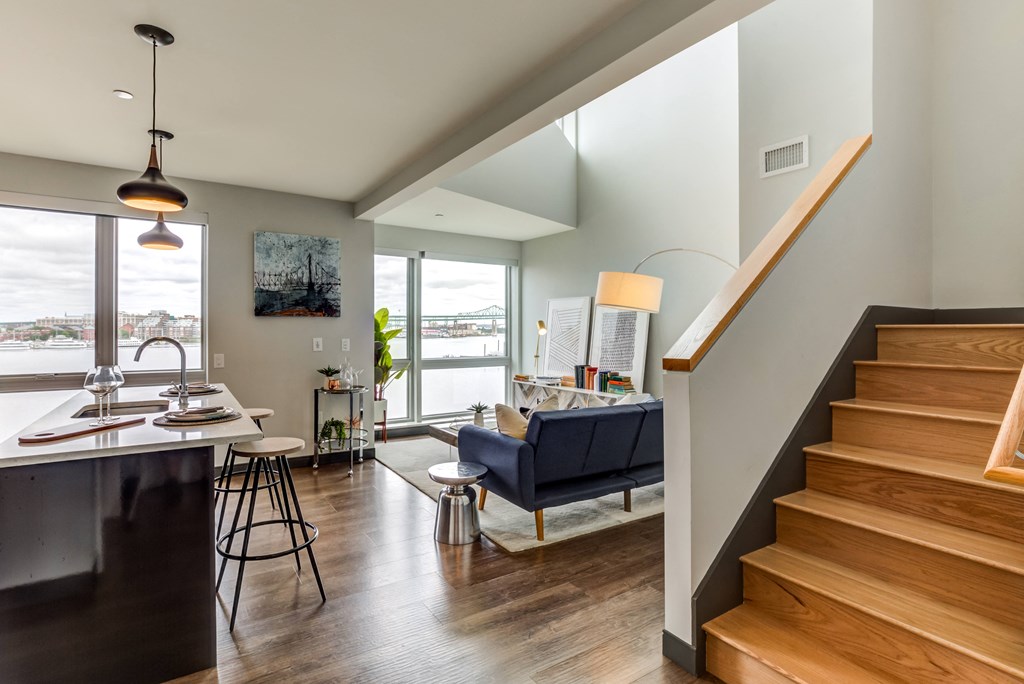 a living room with a staircase and a view of a kitchen and living room