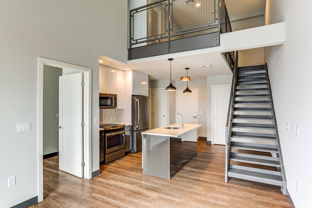 a living room with a staircase and a kitchen