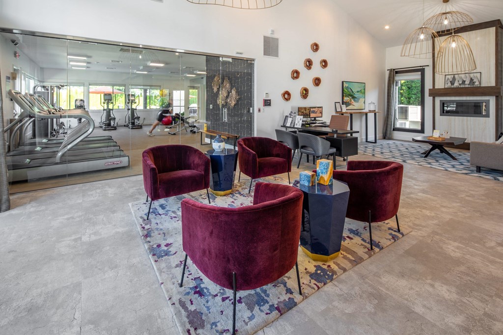 a lobby with chairs and tables and a gym with a treadmill