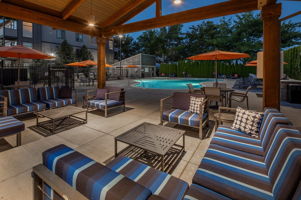 a large patio with chairs and umbrellas near a swimming pool
