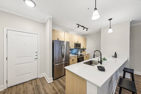a kitchen with a large island and stainless steel refrigerator