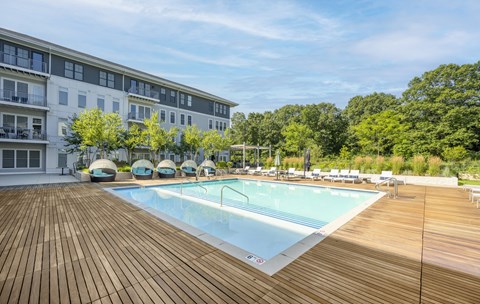 a swimming pool with a wooden deck and a building in the background