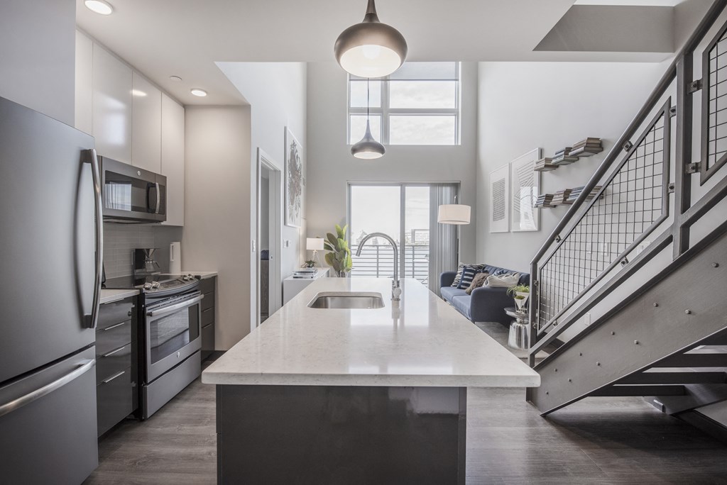 a kitchen with a white counter top and a staircase