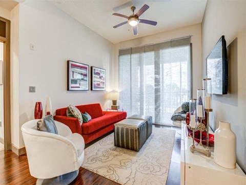 a living room with a red couch and a ceiling fan