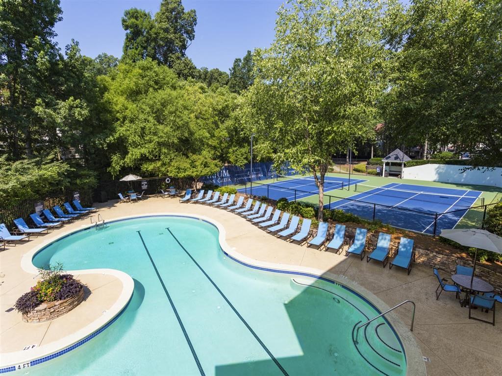 a swimming pool with chairs around it and a tennis court