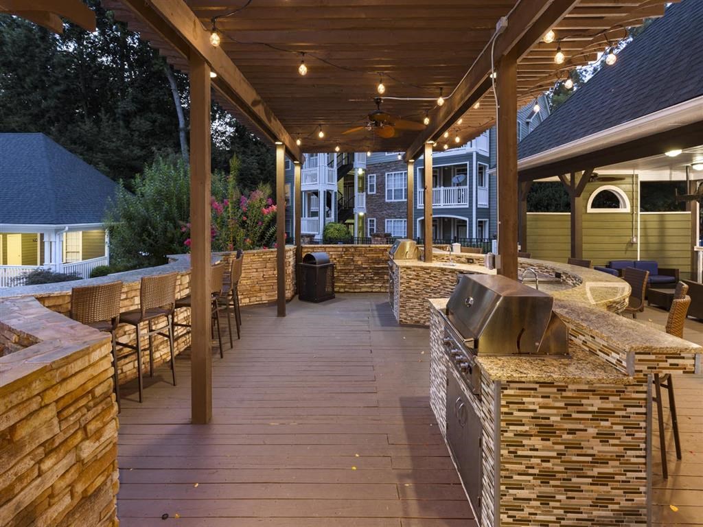 a covered patio with a grill and tables and chairs