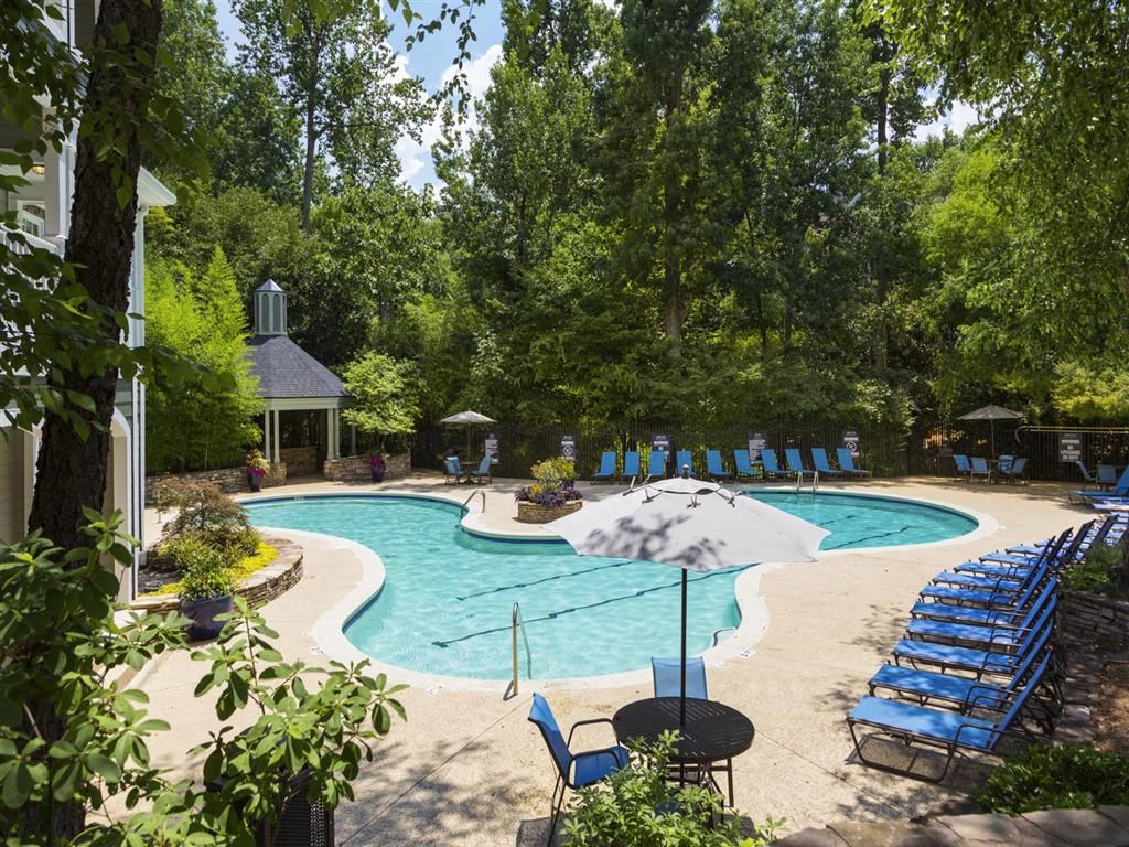 a swimming pool with chairs and an umbrella